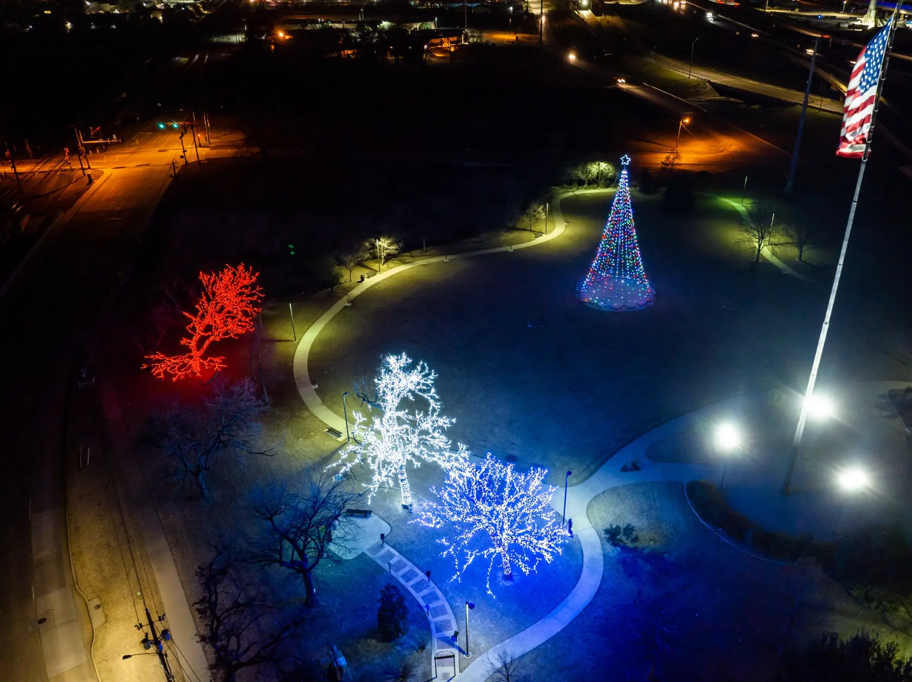 Aerial view of a colorful outdoor holiday display with illuminated trees and cone-shaped features