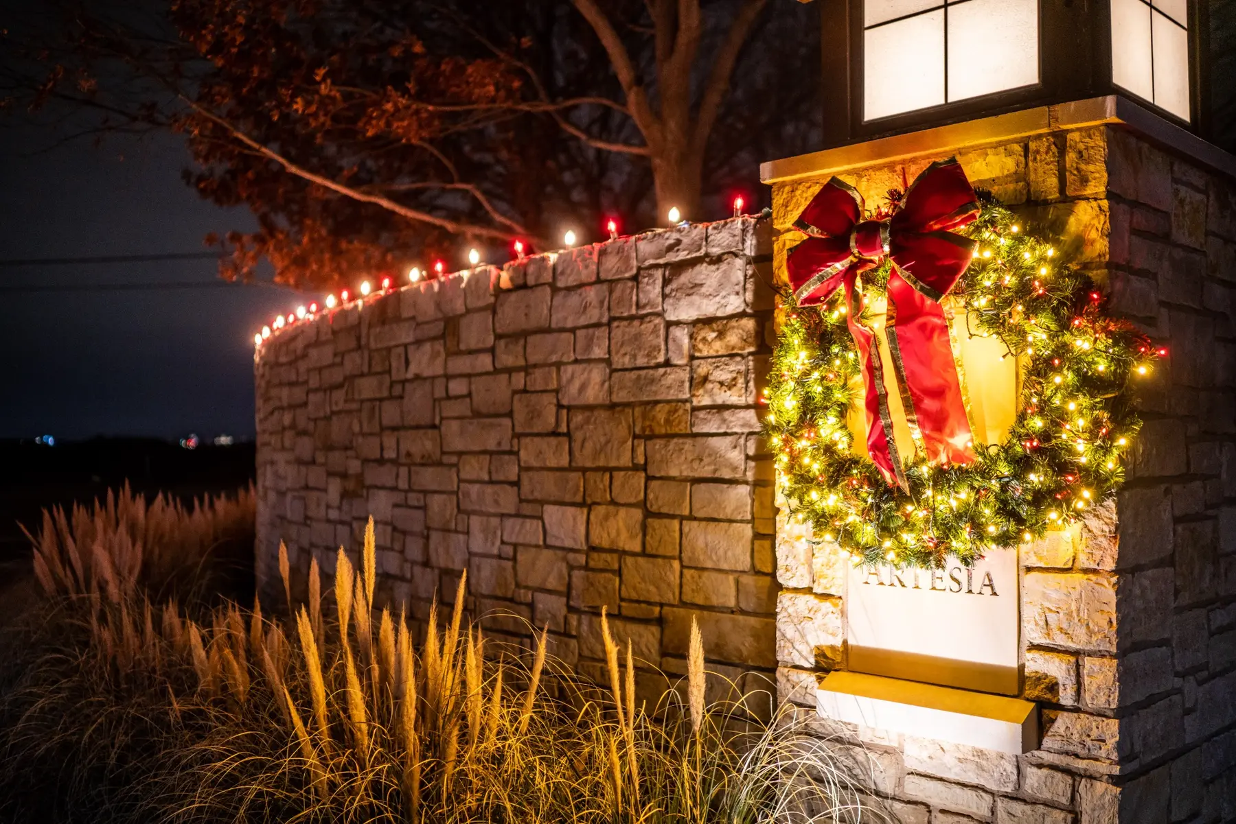 Stone monument with a lit wreath, red bow and red-and-white roofline lights