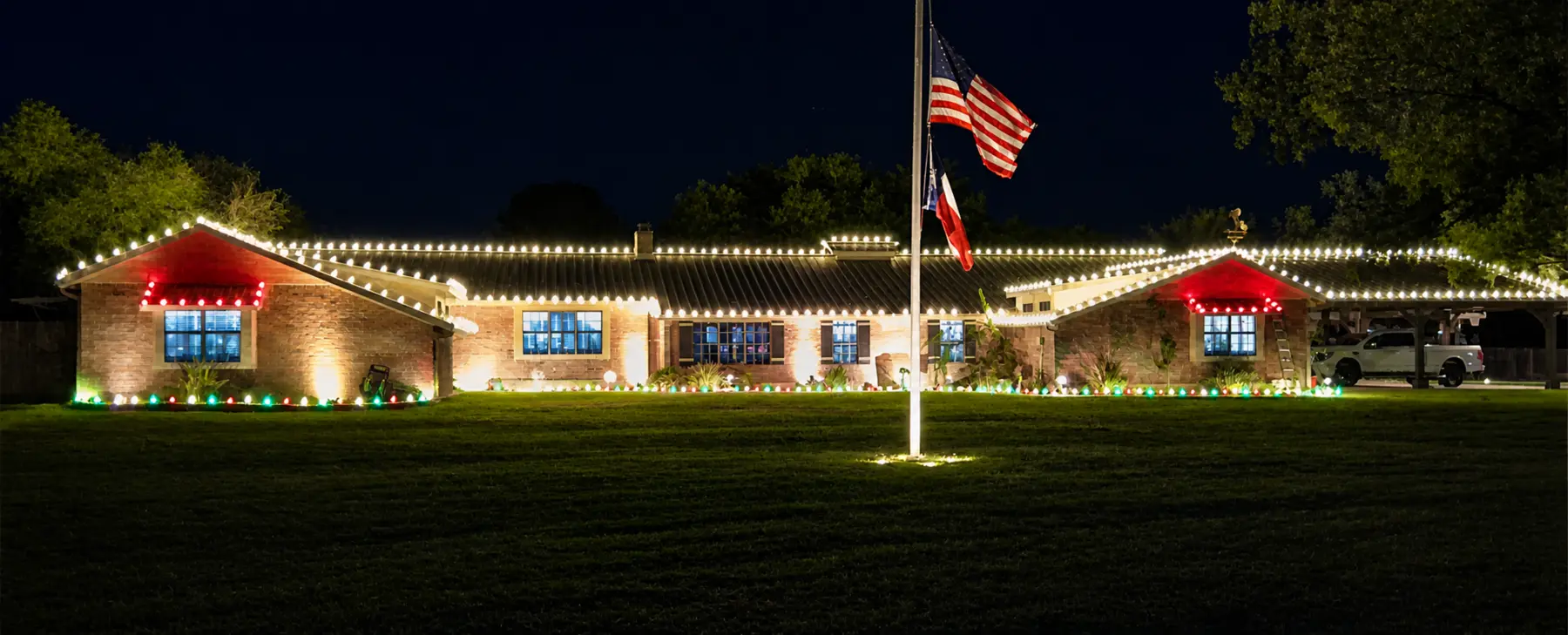 Single-story building with warm white roofline lights and red holiday accents at the entrances