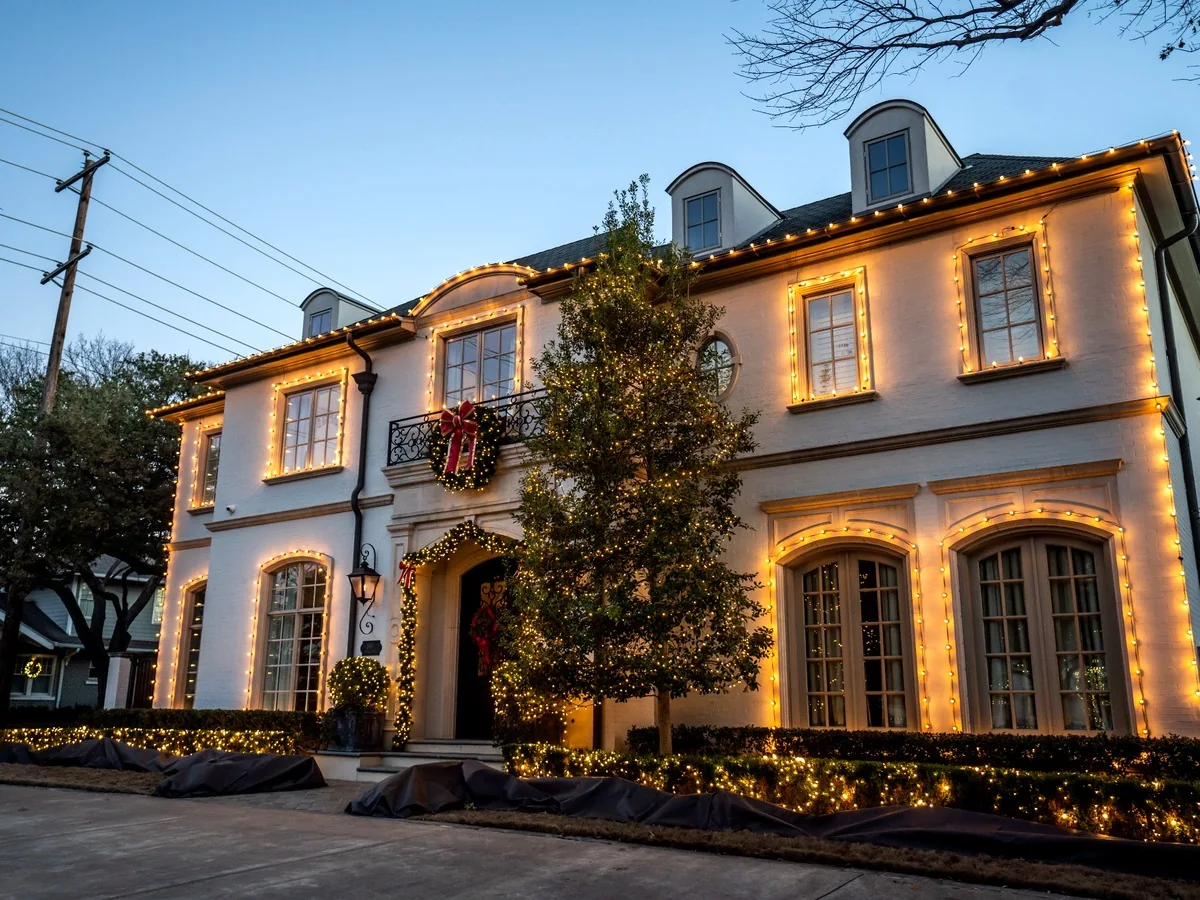 Two-story home with warm white roofline and architectural holiday lighting at dusk
