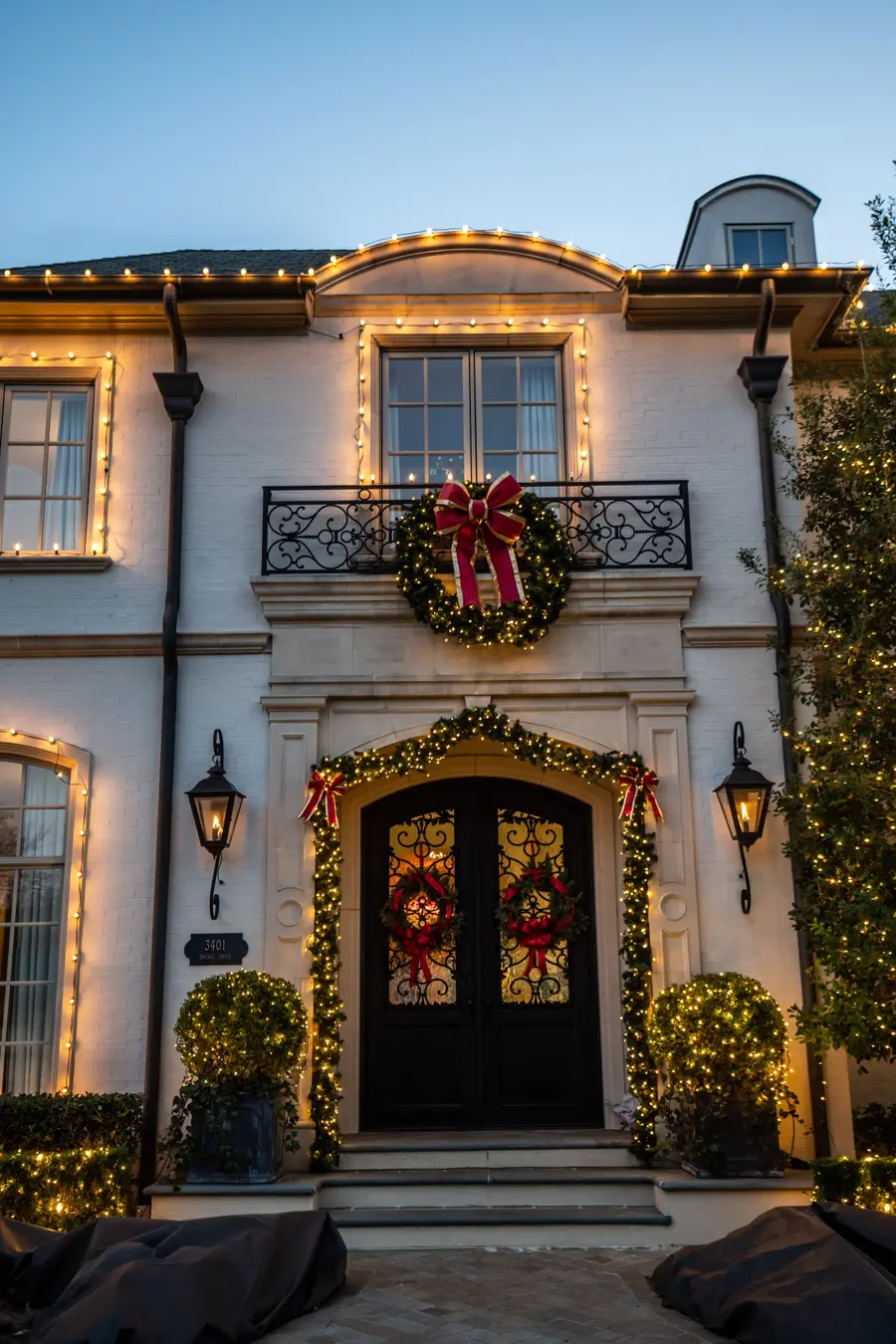 Residential front entry with a wreath, greenery and warm white holiday lighting
