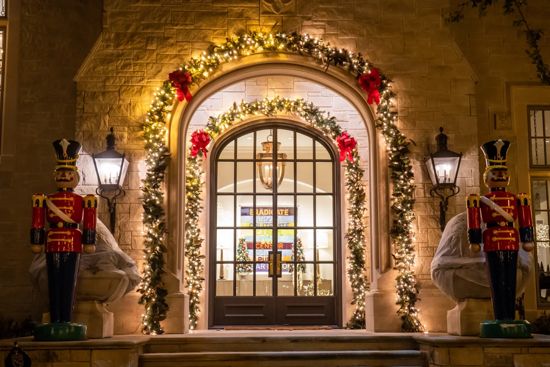 Arched residential entry framed with garland, warm white lights and nutcracker decorations