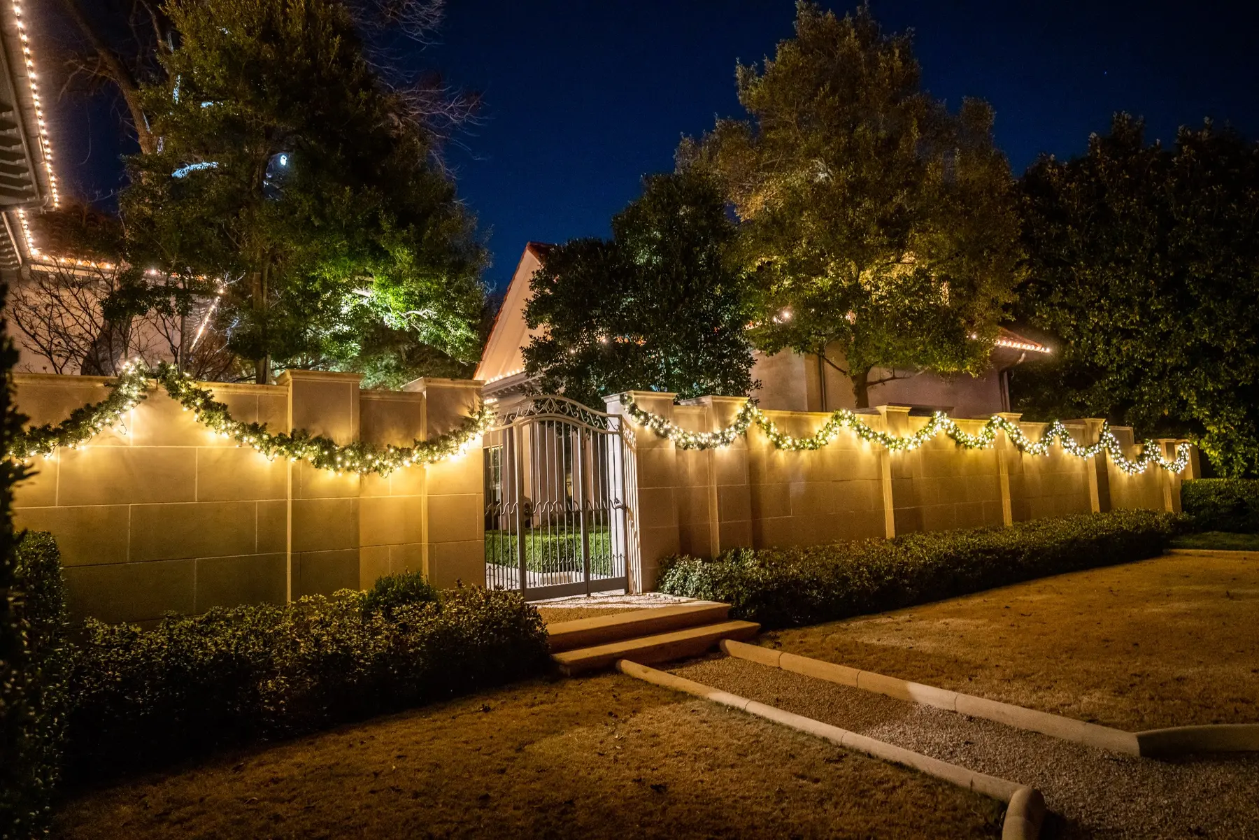 Warm white perimeter stake lighting along a residential side yard and gate