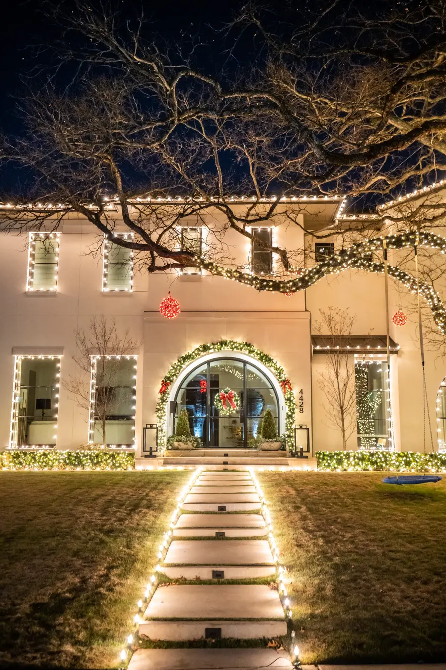Two-story home with warm white roofline, window and walkway lighting