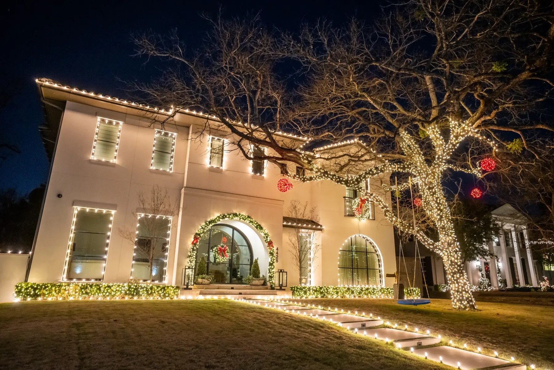 Two-story home with warm white roofline, window and landscape lighting