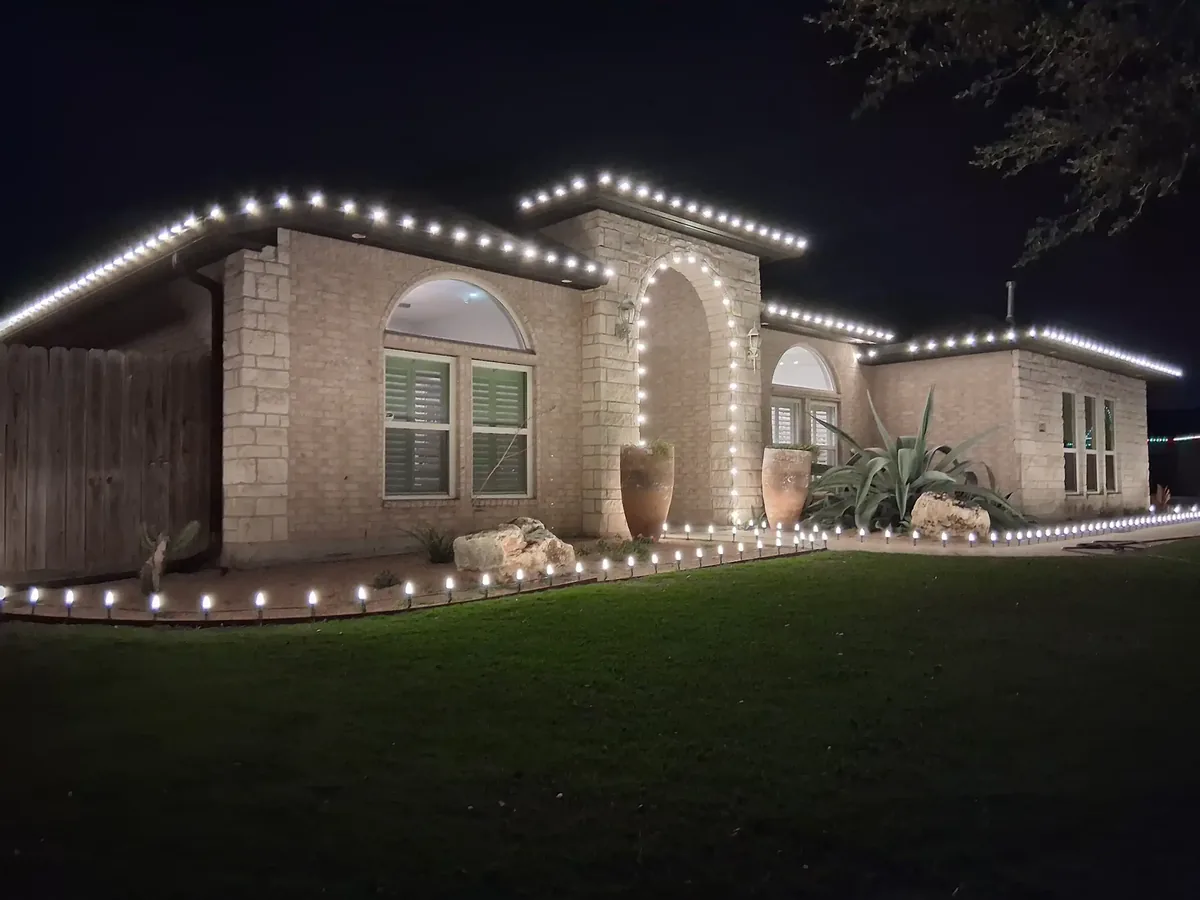 Holiday roofline and walkway lighting coordinated across a residential property